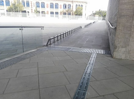 Walkway with a detectable warning surface next to the hand railing