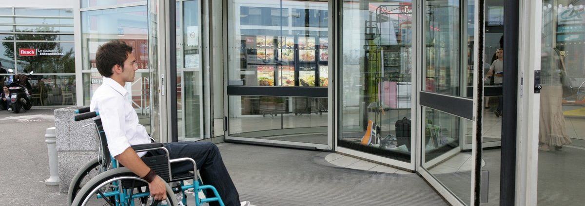 man in wheelchair in front of a shopping store
