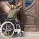 woman in wheelchair in front of entrance door trying to get in