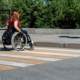 A young woman in a wheelchair in front of a high curb at a pedestrian crossing