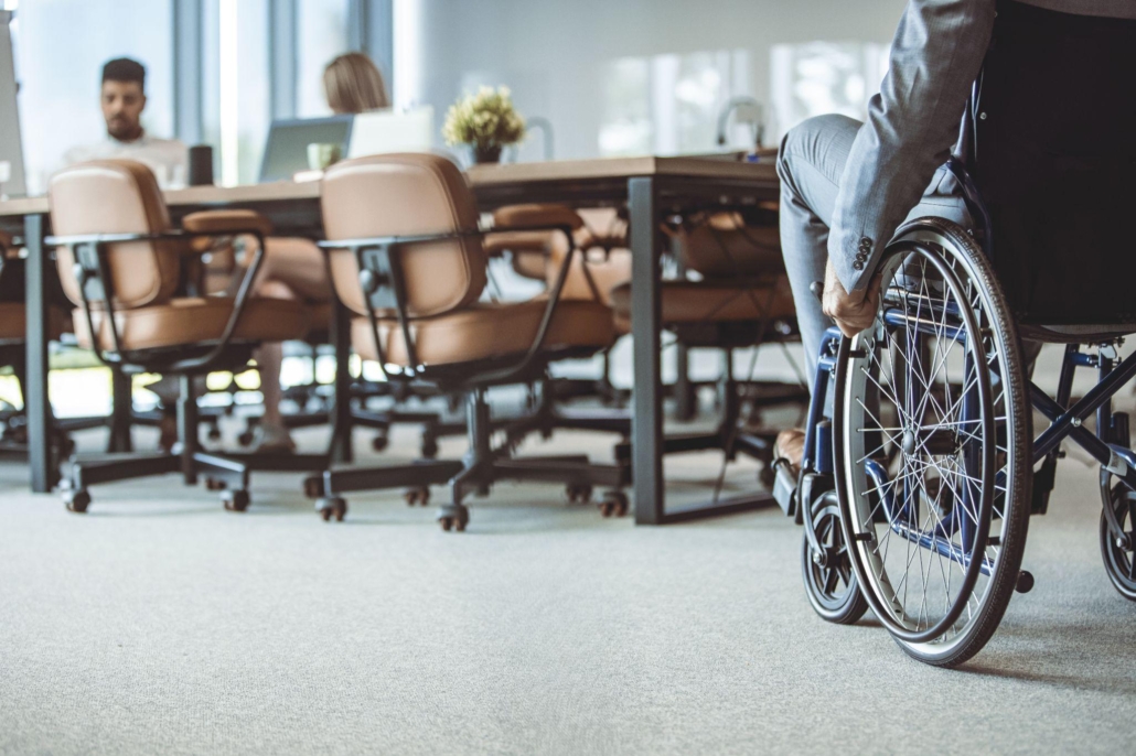 man in wheelchair approaches colleagues in office