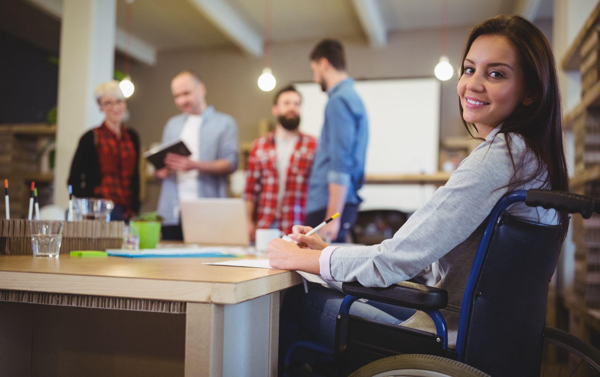 Portrait of confident disabled businesswoman writing at desk in creative office