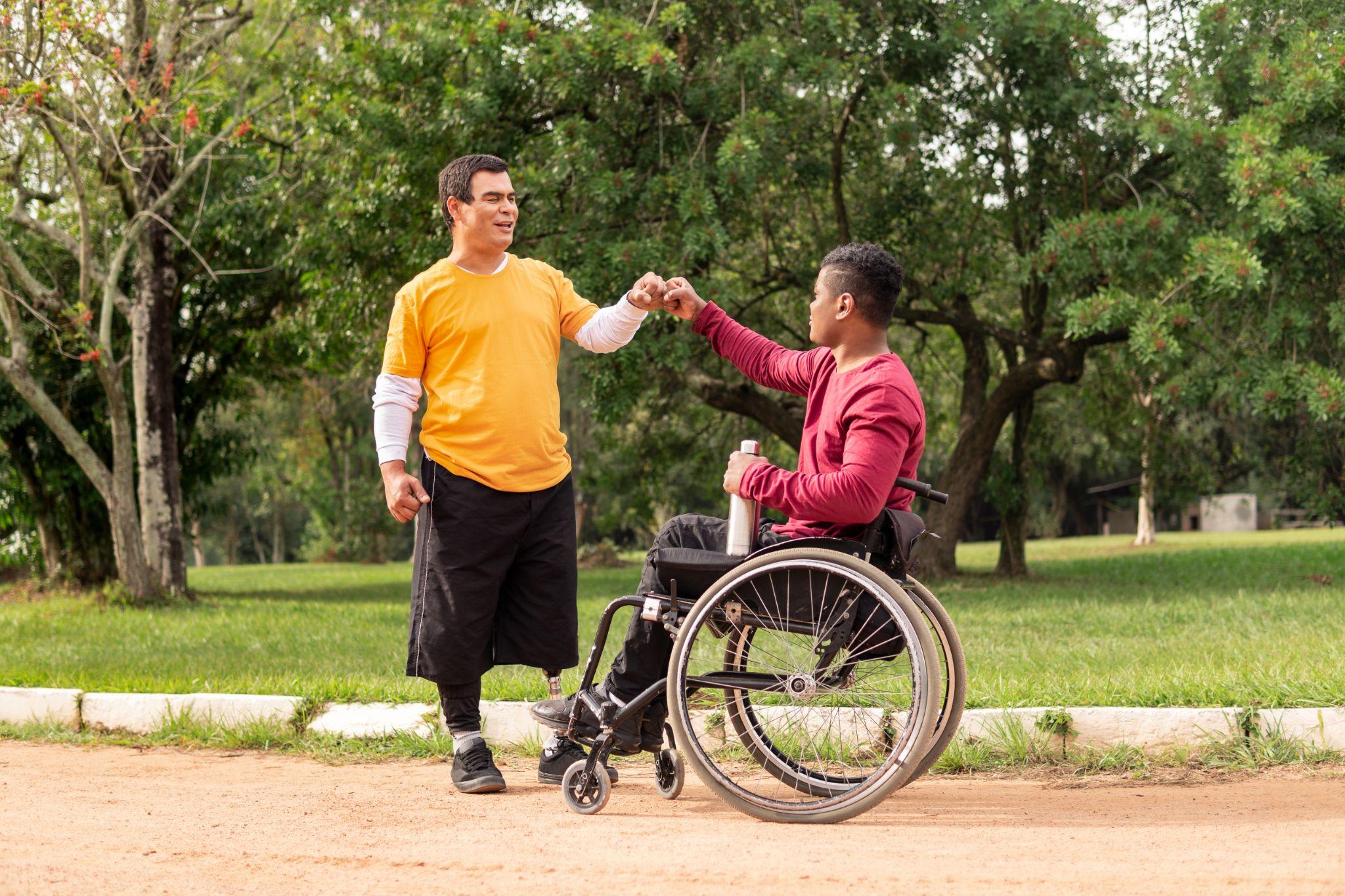 person in wheelchair greeting friend in the park